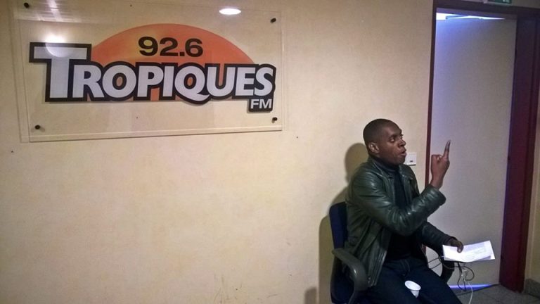 Claudy Siar devisant avec des journalistes à l’entrée de Tropiques FM