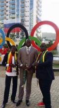 Frank Elemba devant les anneaux olympiques avec Cécilia Bouélé et monsieur Tamba, le directeur technique du Comité olympique congolais